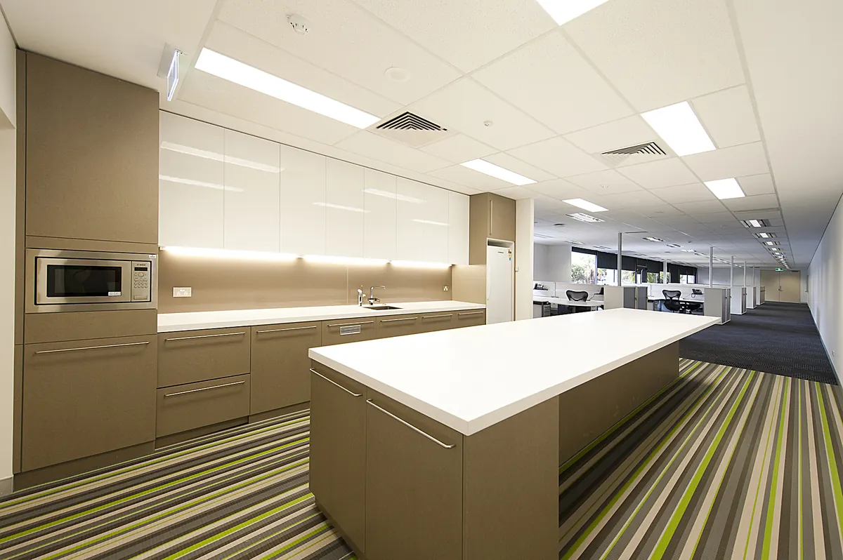 NBN workplace fitout — completed staff kitchen and open-plan floor with striped carpet.